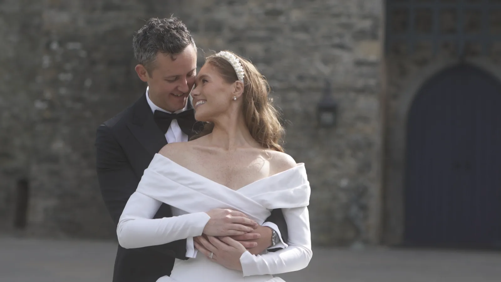 Bride and groom embracing in front of a castle doorway