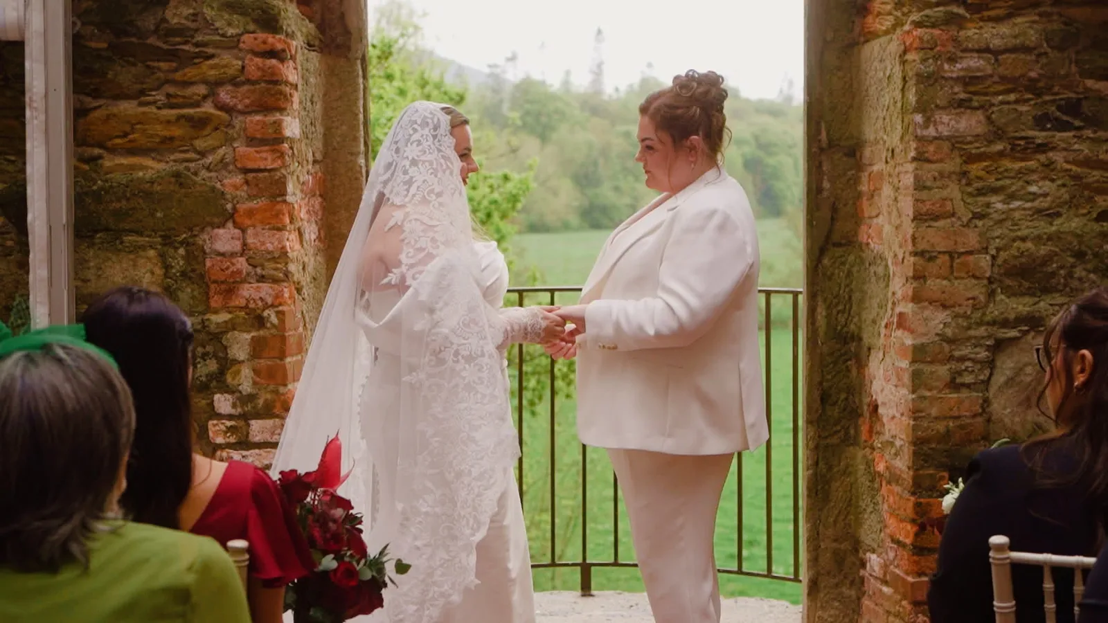 Same-sex couple exchanging vows during an outdoor ceremony