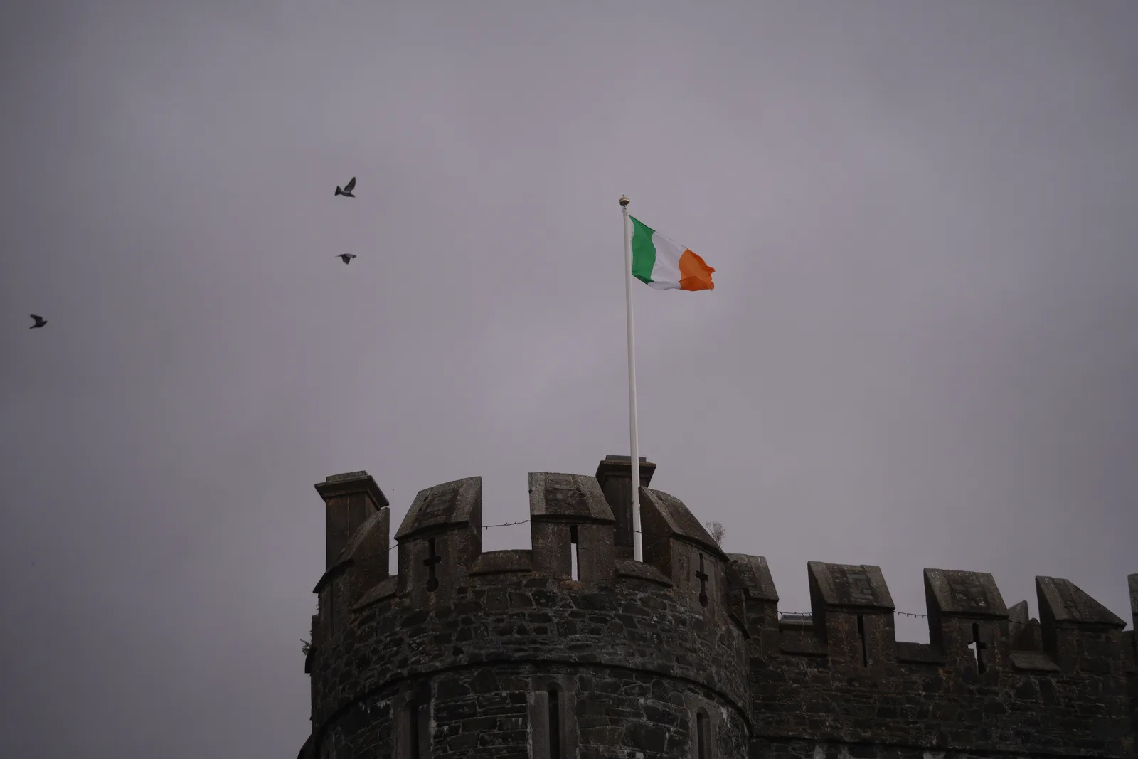 The battlements at Kilkea Castle with the Irish tricolour flying against a grey sky