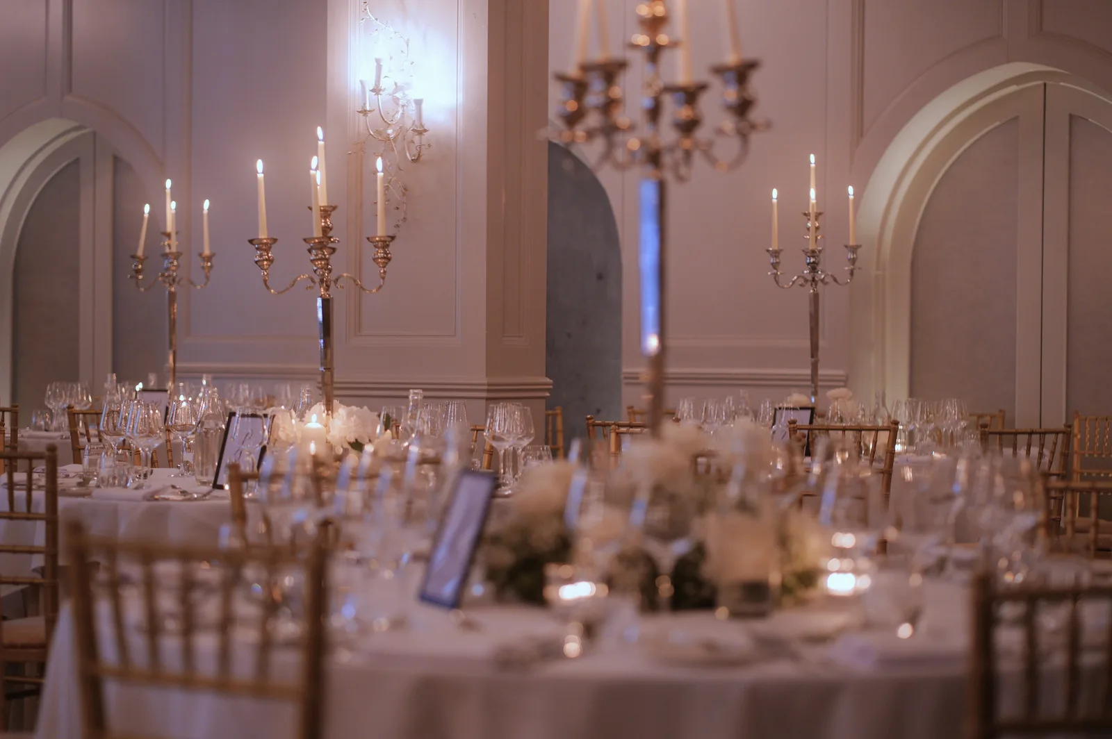 Round tables at a Kilkea Castle wedding reception, tall candelabra and soft light in the panelled room