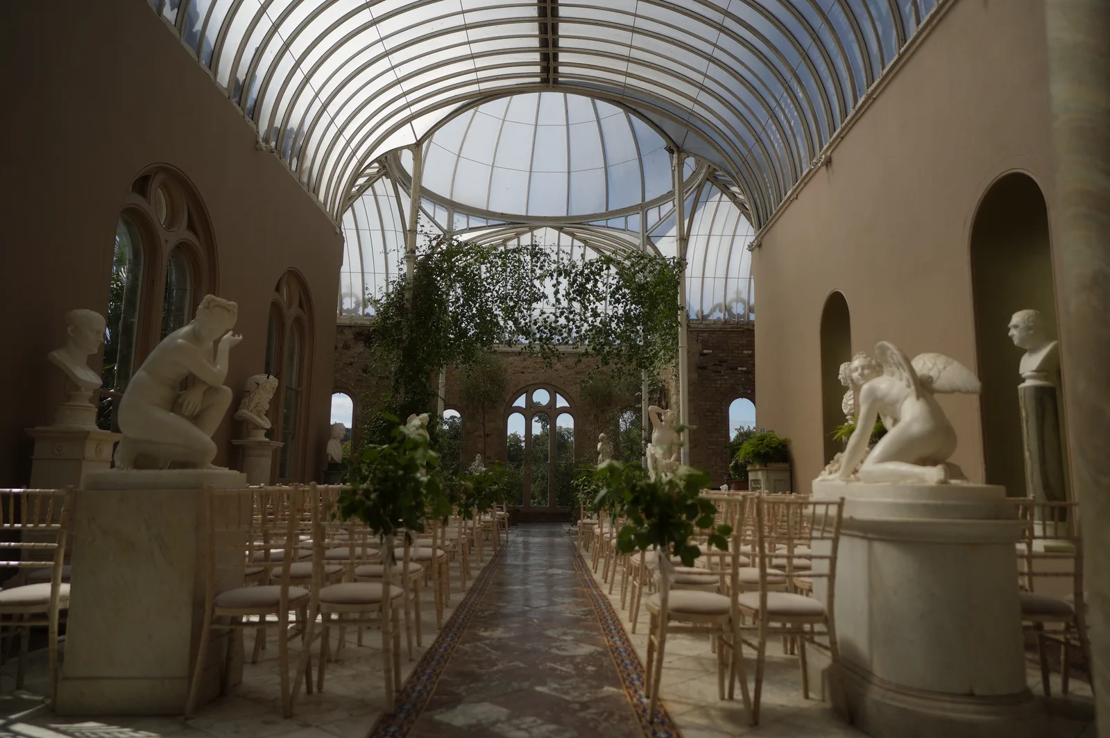 The Orangery at Killruddery set for a wedding ceremony, with an aisle running between marble statues under the glass roof