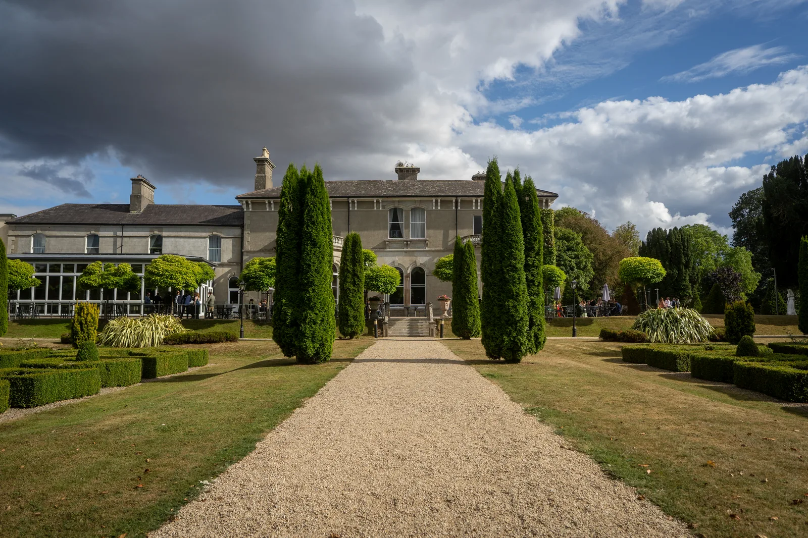 The formal gravel approach to Lyrath Estate's original house, clipped box hedging either side under a dramatic sky