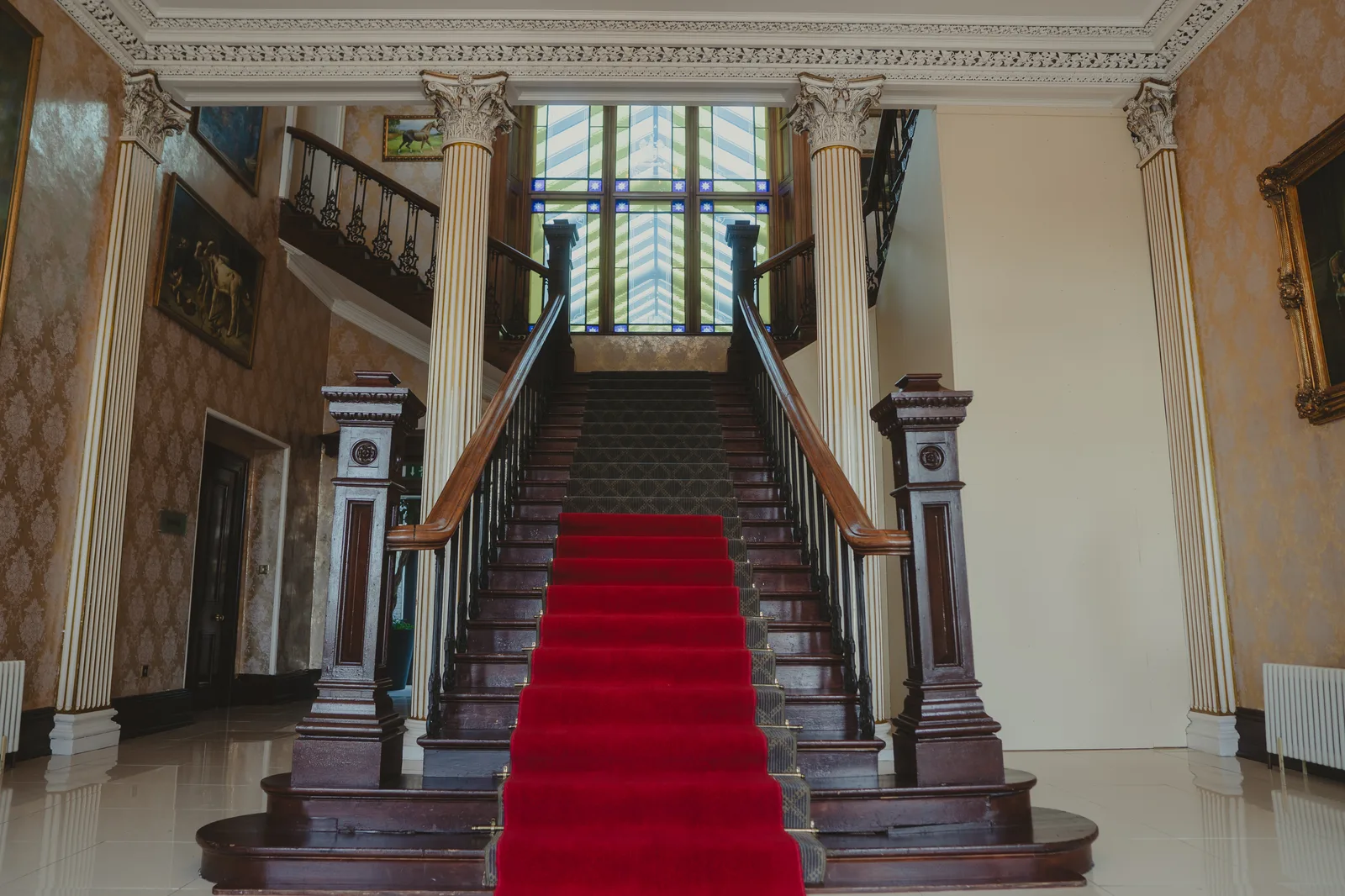 The red-carpet staircase inside the original Lyrath House, Corinthian columns and a stained-glass roof light above
